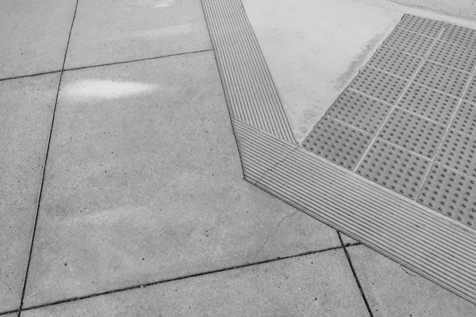 Grey concrete curb ramp with small bumps for the visually impaired.